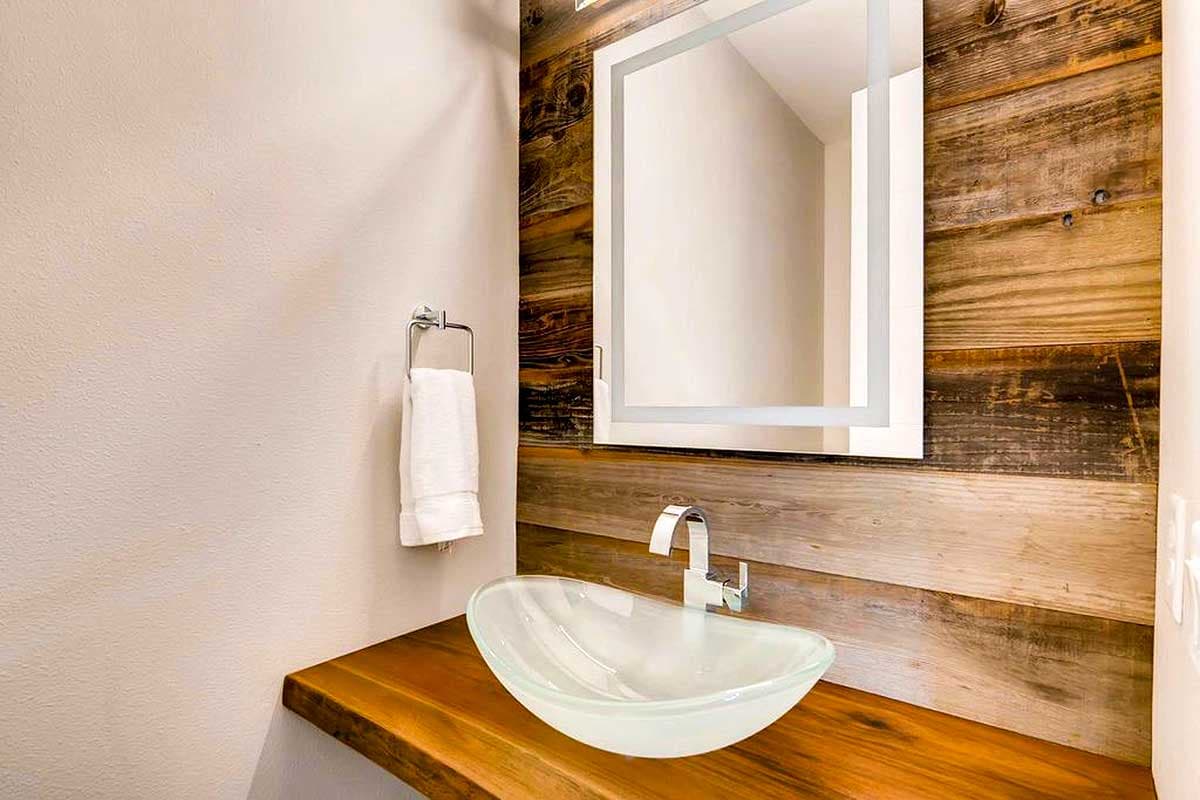 Bathroom vanity with glass vessel sink, live-edge wood countertop, and rustic wood accent wall.