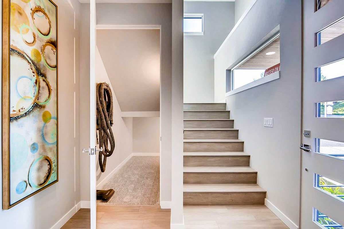 Modern entryway with open staircase, transom windows, and open storage area.