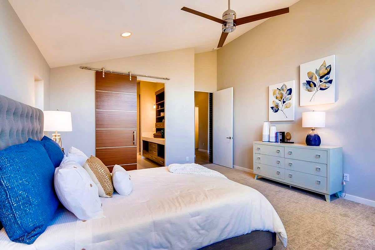 Bedroom with vaulted ceiling, ceiling fan, and sliding barn door to walk-in closet.