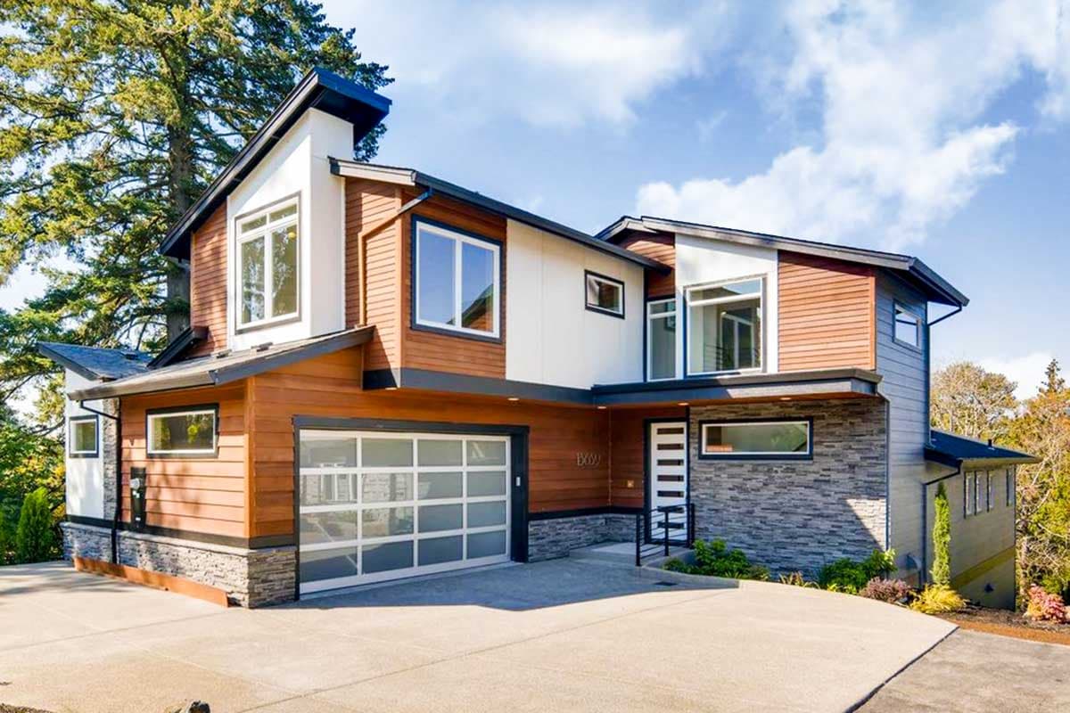 Modern two-story house plan exterior with wood siding, stone accents, large windows, and a glass garage door.