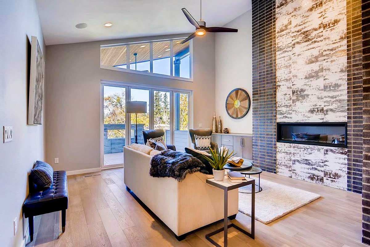 Living room with vaulted ceiling, large windows, and a floor-to-ceiling brick fireplace with linear gas insert.