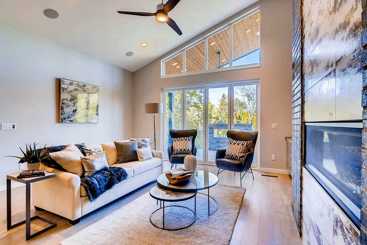 Living room with a vaulted ceiling, clerestory windows, fireplace, and large glass doors leading outdoors.