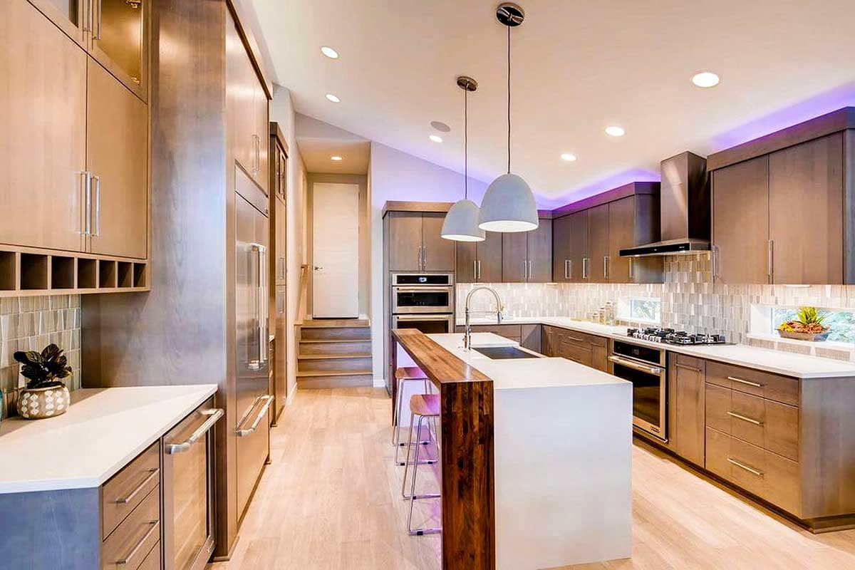 Modern kitchen with island, stainless steel appliances, wood cabinetry, and pendant lighting.