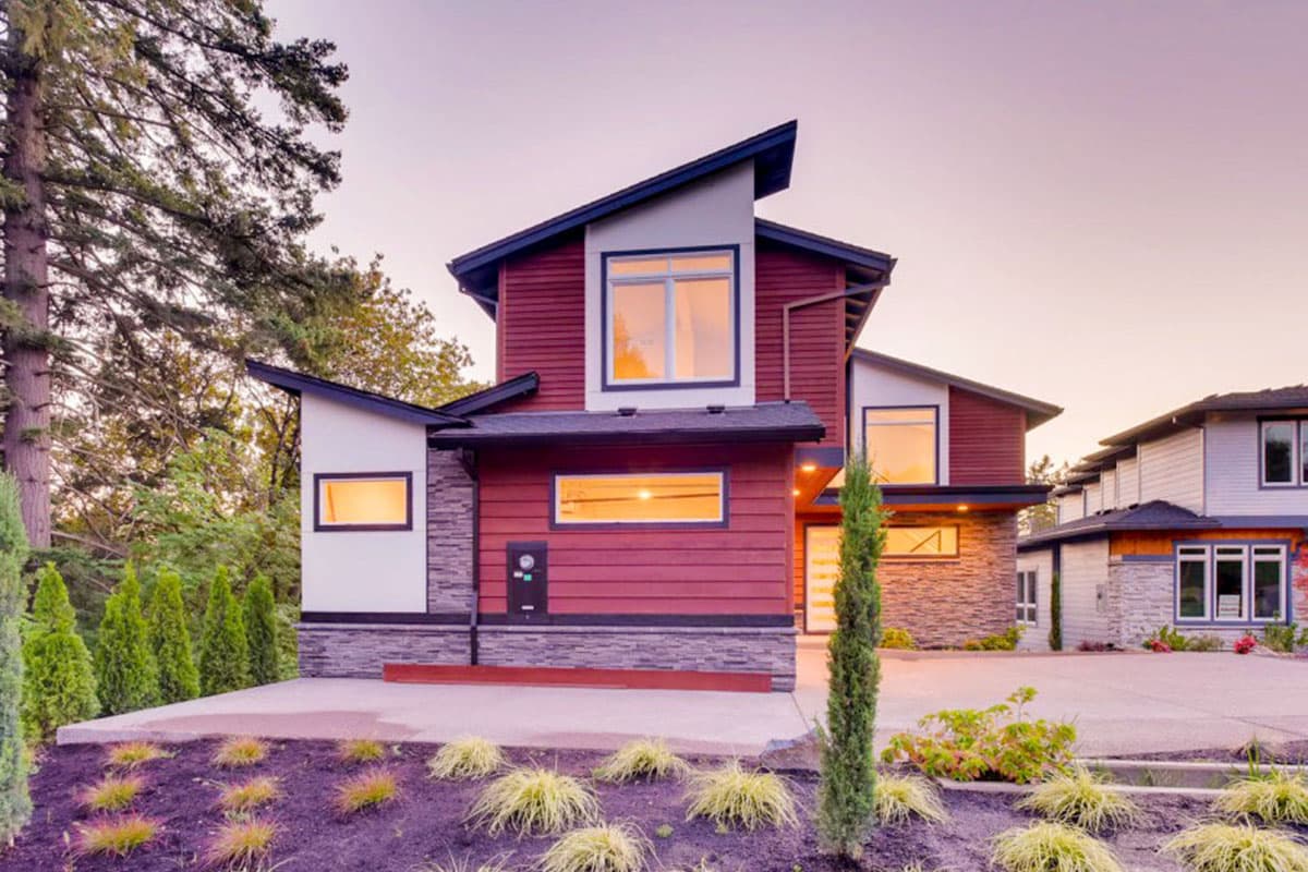 Modern house plan exterior with red horizontal siding, stone accents, and asymmetrical rooflines.