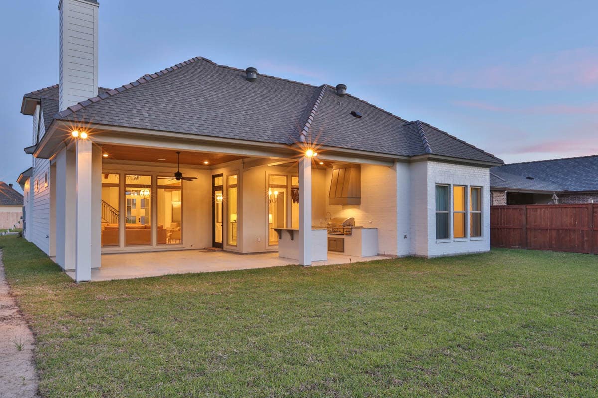 House plan exterior showing covered patio with outdoor kitchen, large windows, and white brick.