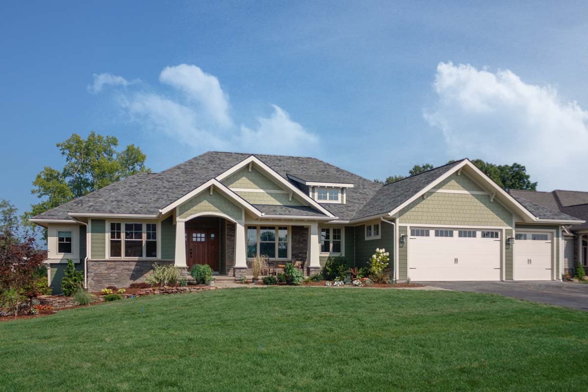 House plan exterior. Craftsman style, one-story home with gabled roof, covered entry porch, and attached garage. Stone and shingle accents.