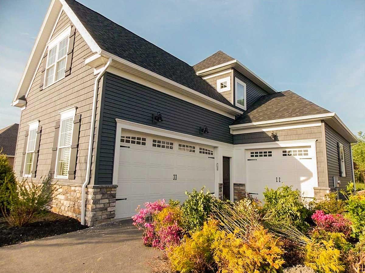 House plan exterior: Two-story Modern Farmhouse with stone accents, dual garage doors, dormers, and prominent gables.