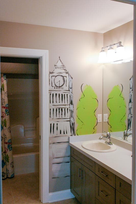 Bathroom with Big Ben mural, vanity with sink and faucet, and view into shower with patterned curtain.
