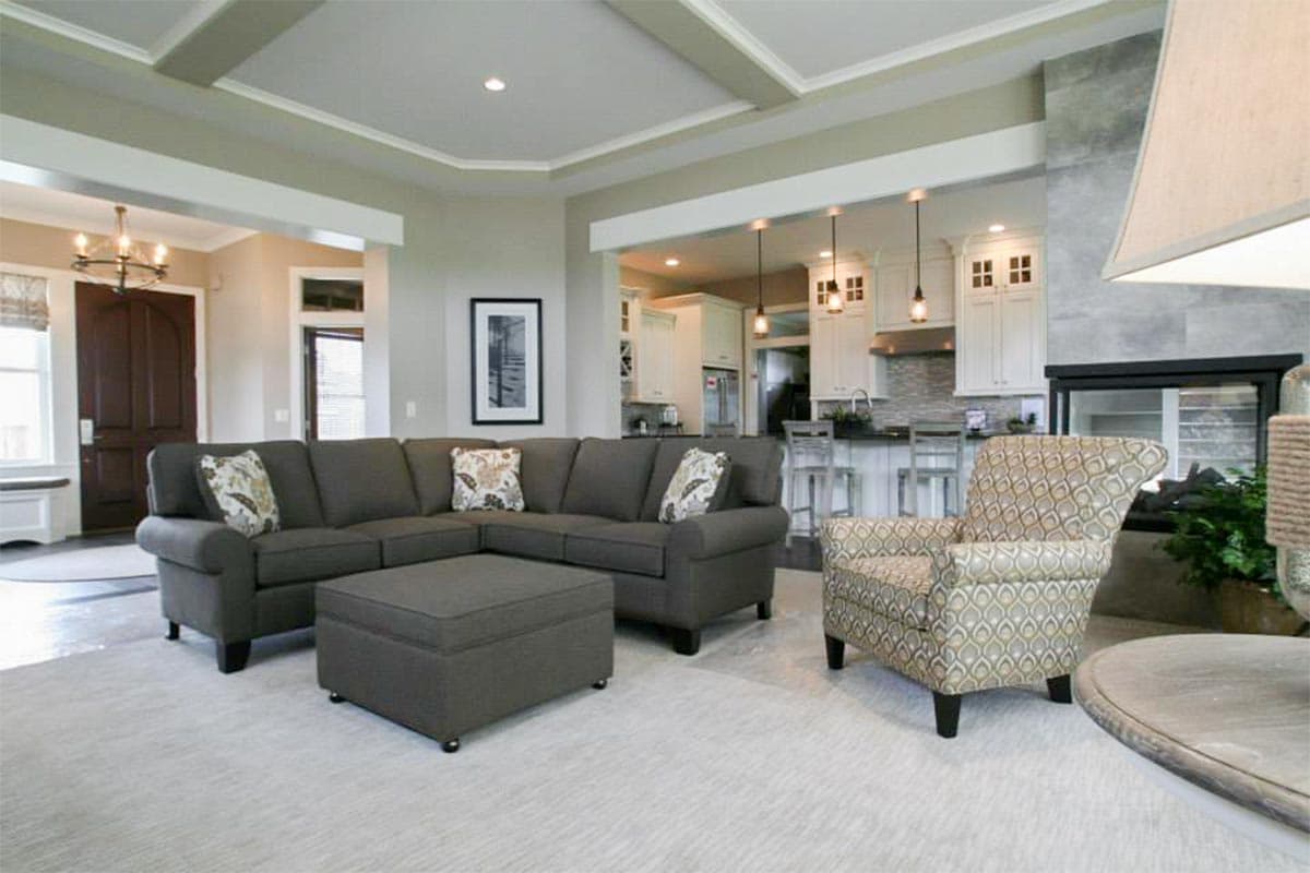 Living room with coffered ceiling, fireplace, and open view to kitchen with island and bar seating.