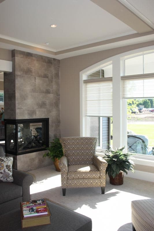 Interior view of living area with corner fireplace, large windows, and patterned armchair.