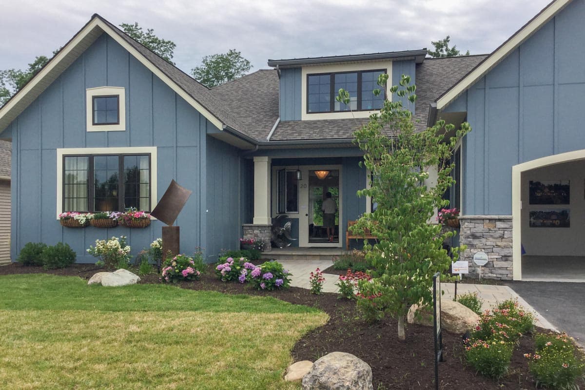 Modern Farmhouse style house plan exterior with a prominent gable, covered porch with stone accents, and a detached garage.