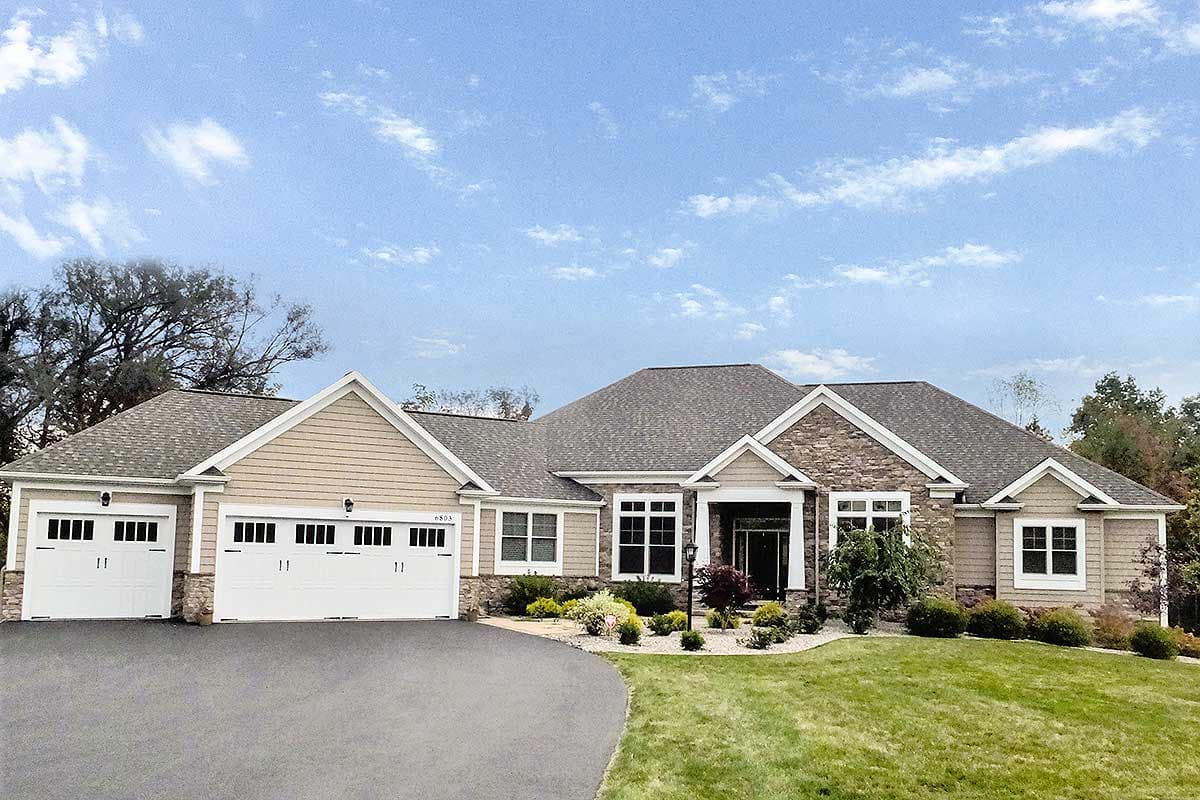 House plan exterior: Ranch style with three-car garage, stone accents, and prominent gables.