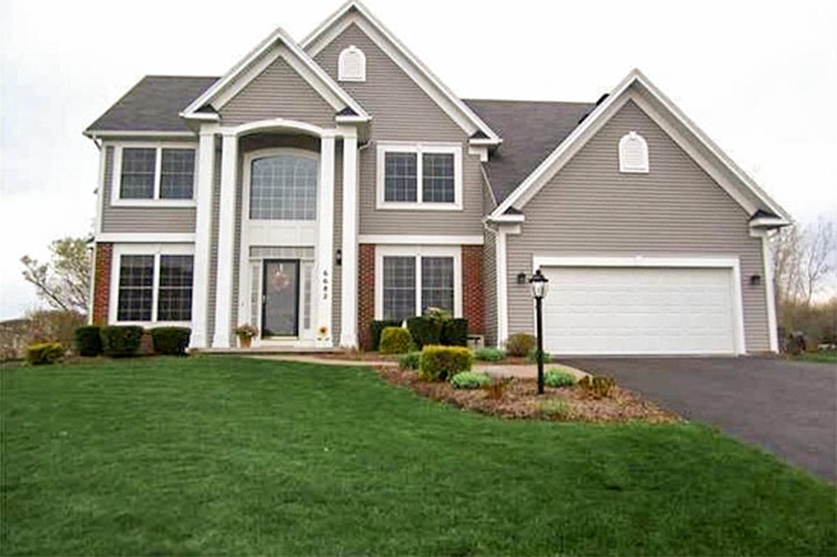 Two-story house plan exterior with arched entryway, dual gables, side-facing garage, and dormer.