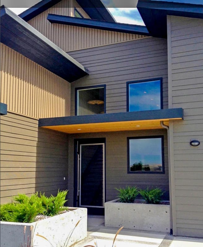 Modern house plan exterior with asymmetric rooflines, wood soffit entryway, and horizontal siding.