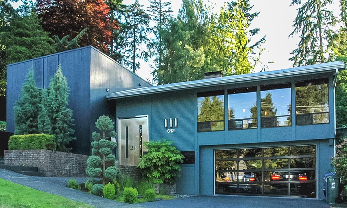 House plan exterior. Modern style, one story, featuring a flat roof, large windows, and a glass-paneled garage door.
