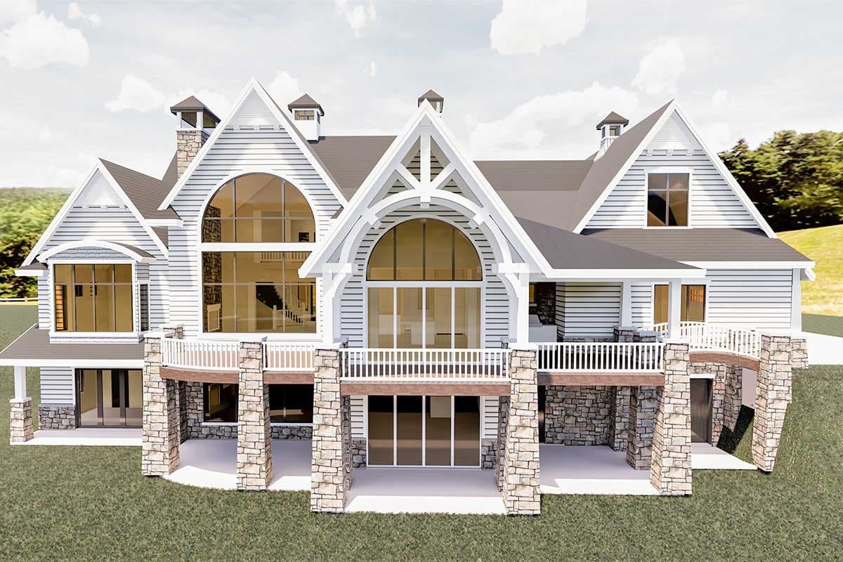 House plan exterior: Modern Farmhouse style with multiple gables, stone accents, wraparound deck, and large arched windows.