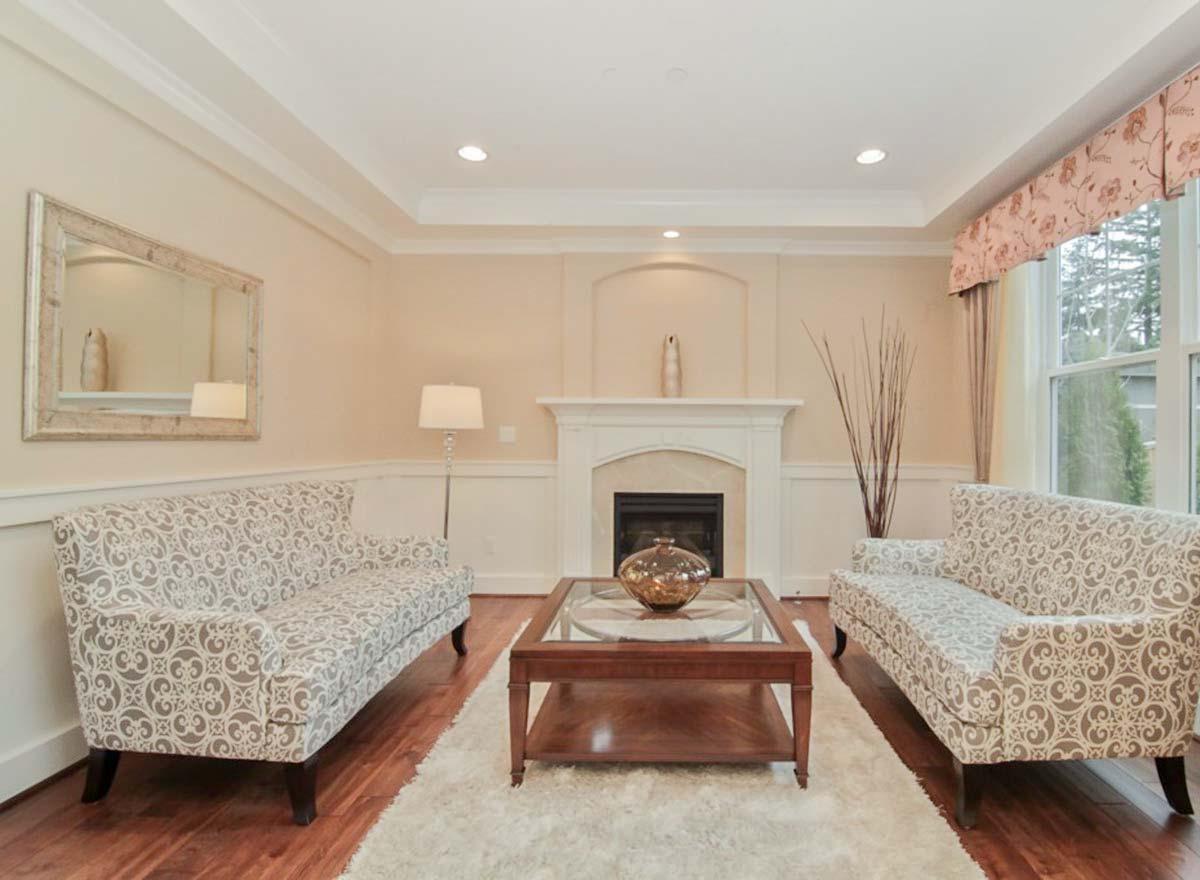 Living room interior with fireplace, two sofas, coffee table, and large mirror on wall.