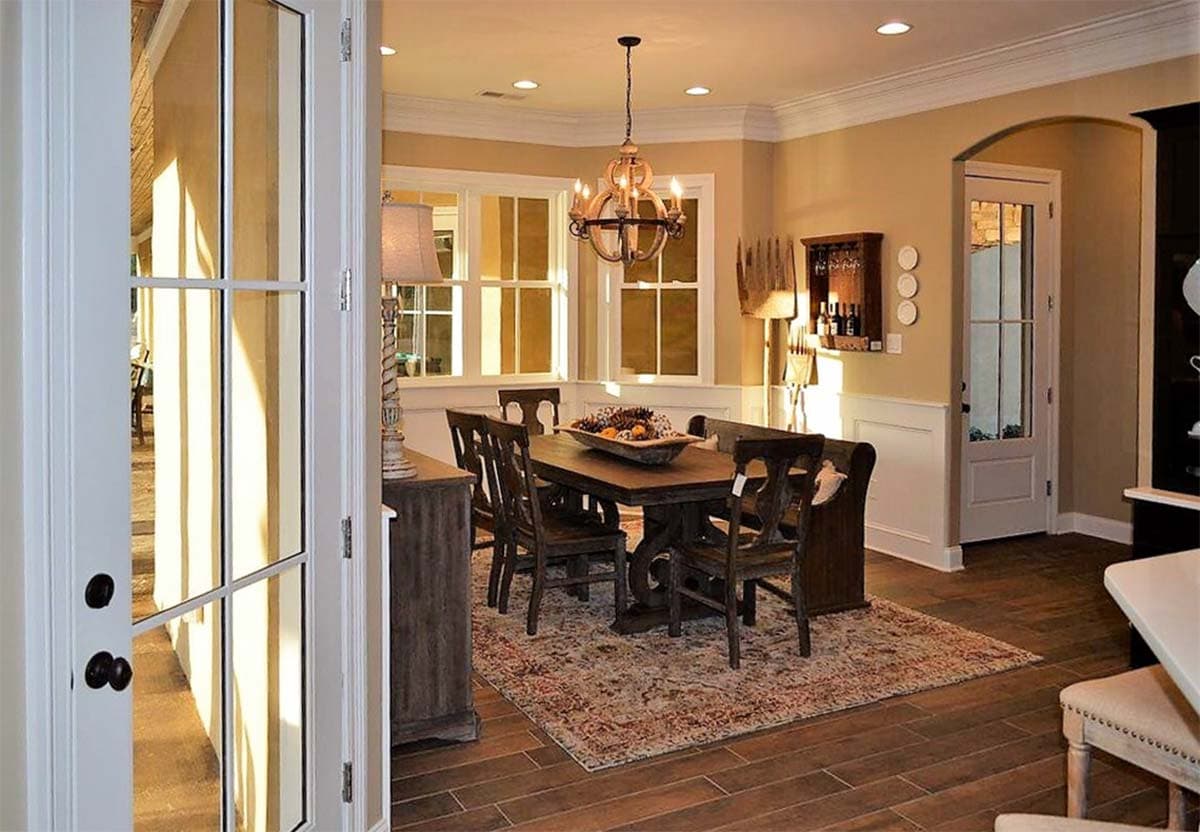 Dining room with dark wood table and chairs, paneled wainscoting, and multi-pane windows.
