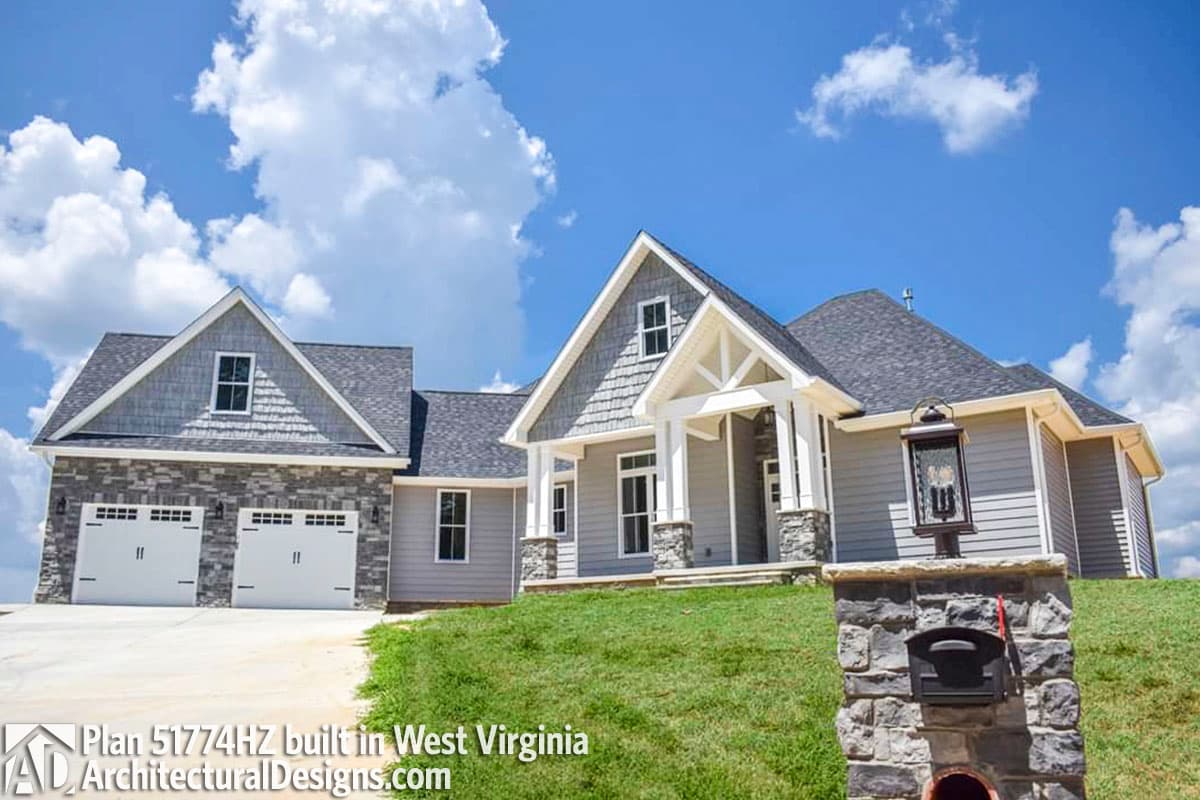 House plan exterior: two-story, gable rooflines, stone accents, and a three-car garage.
