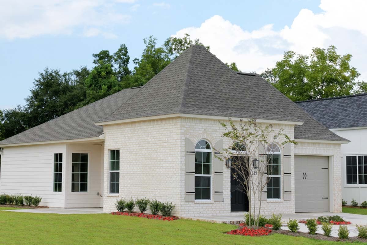 House plan exterior of one-story home with white brick and siding, arched windows, and attached garage.