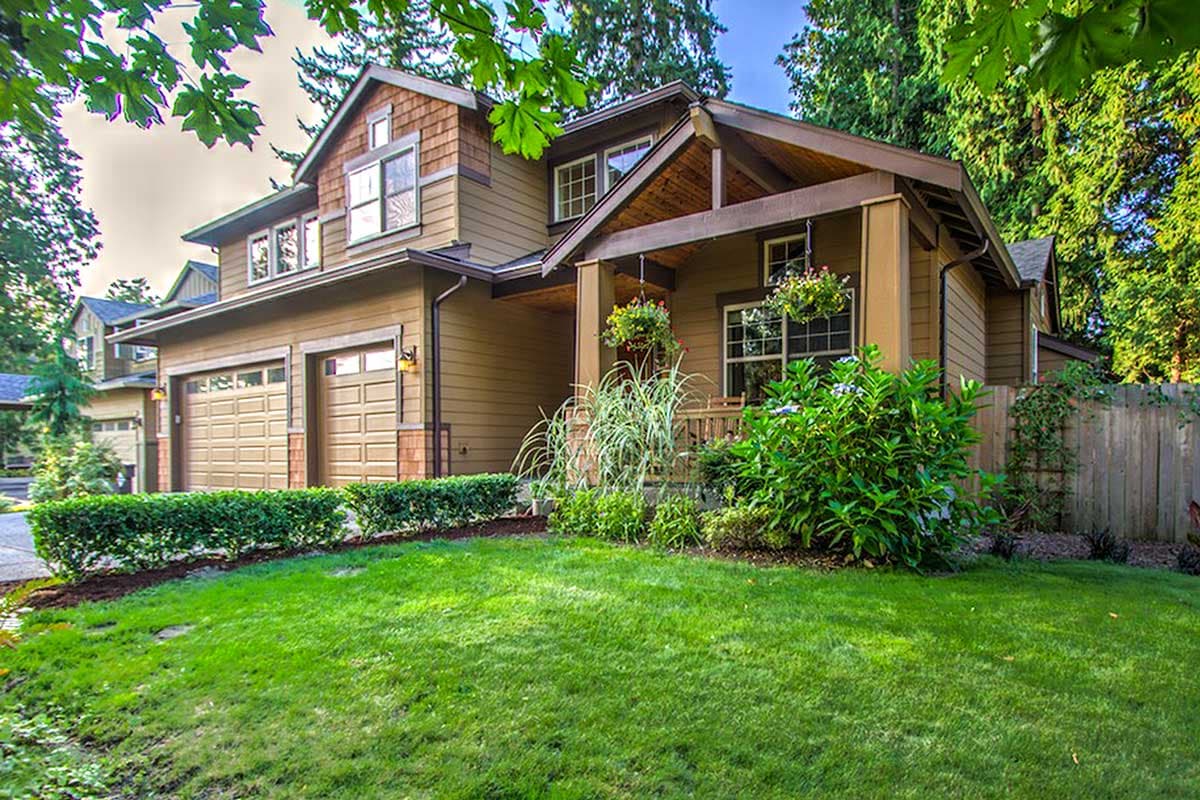 House plan exterior: Craftsman style, two stories, dual garage doors, covered porch with exposed beams, and dormer windows.