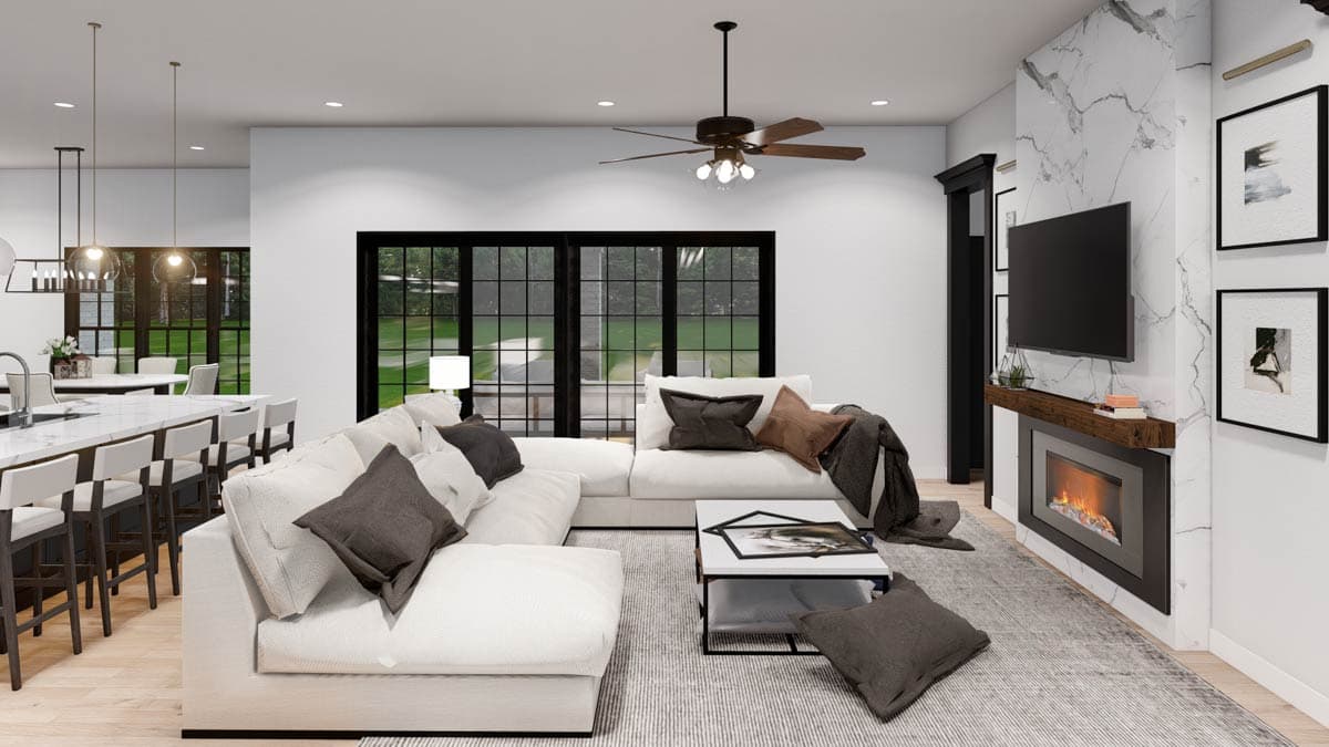 Open concept living area with sectional sofa, fireplace with marble surround, and large windows.