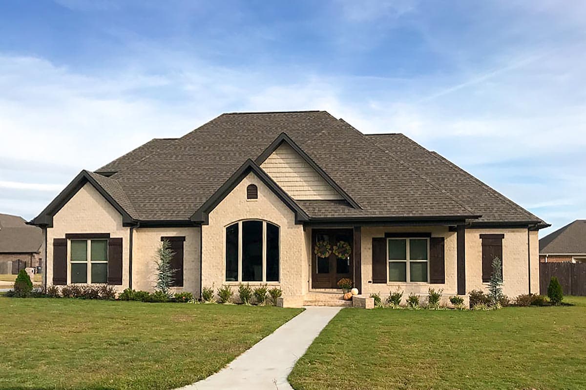 House plan exterior: Ranch style, one story, stucco finish, prominent gables, arched window, and shutters.