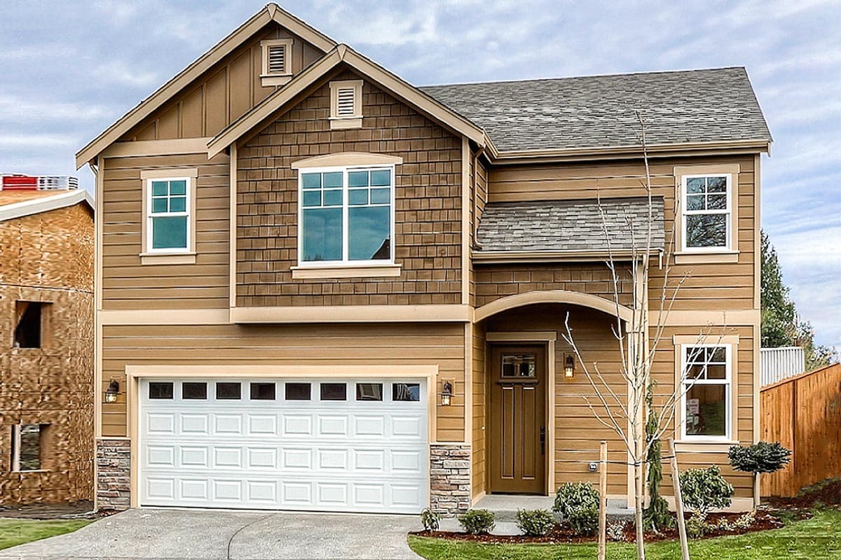 House plan exterior featuring a two-story design with a gable roof, shake siding, and a covered front entry.