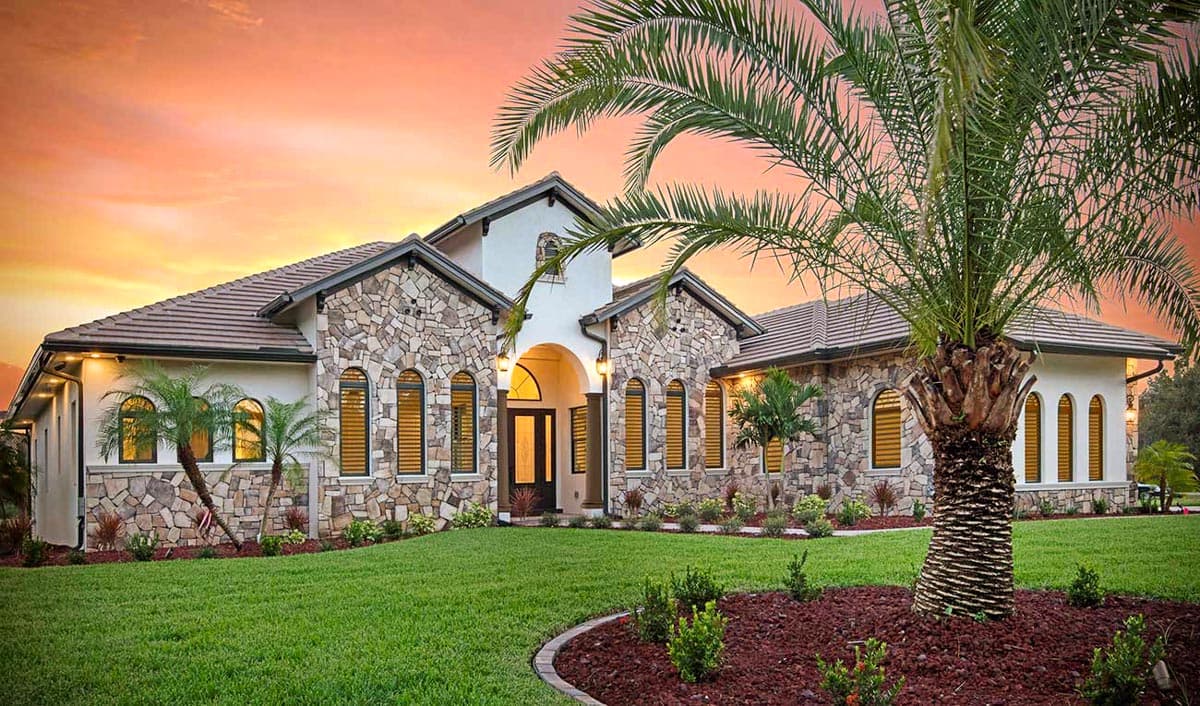 House plan exterior: single-story home with stone facade, arched windows, tiled roof, and covered entryway with columns.