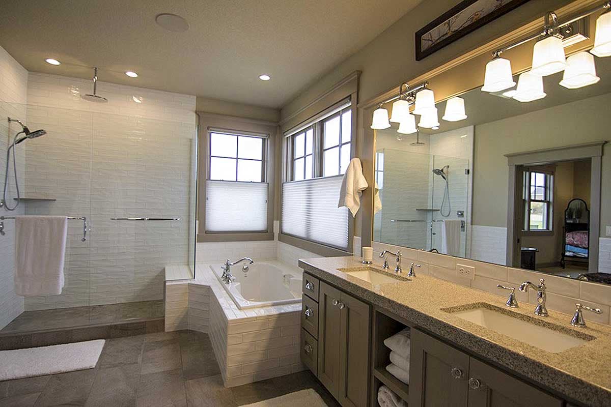 Bathroom with dual vanities, undermount sinks, large vanity mirror, freestanding tub, and glass-enclosed tiled shower.
