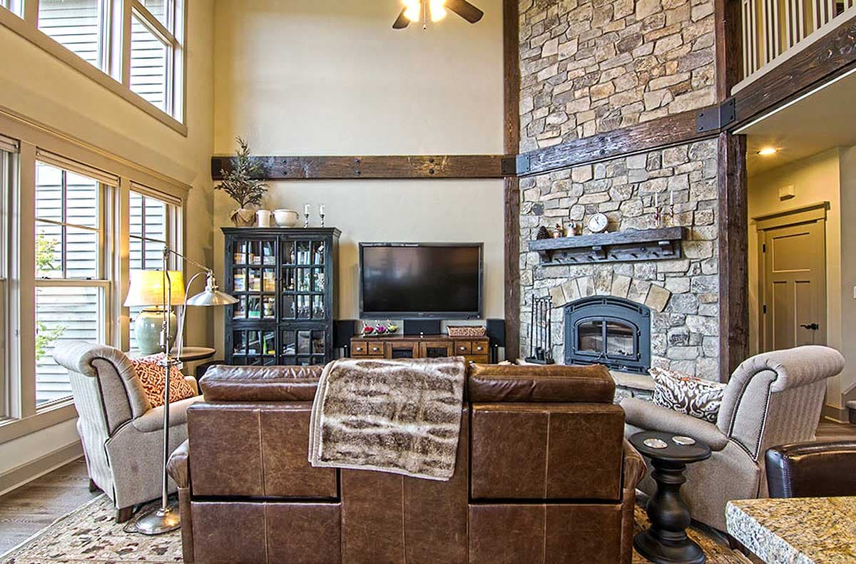 Living room with vaulted ceiling, stone fireplace, and large windows.