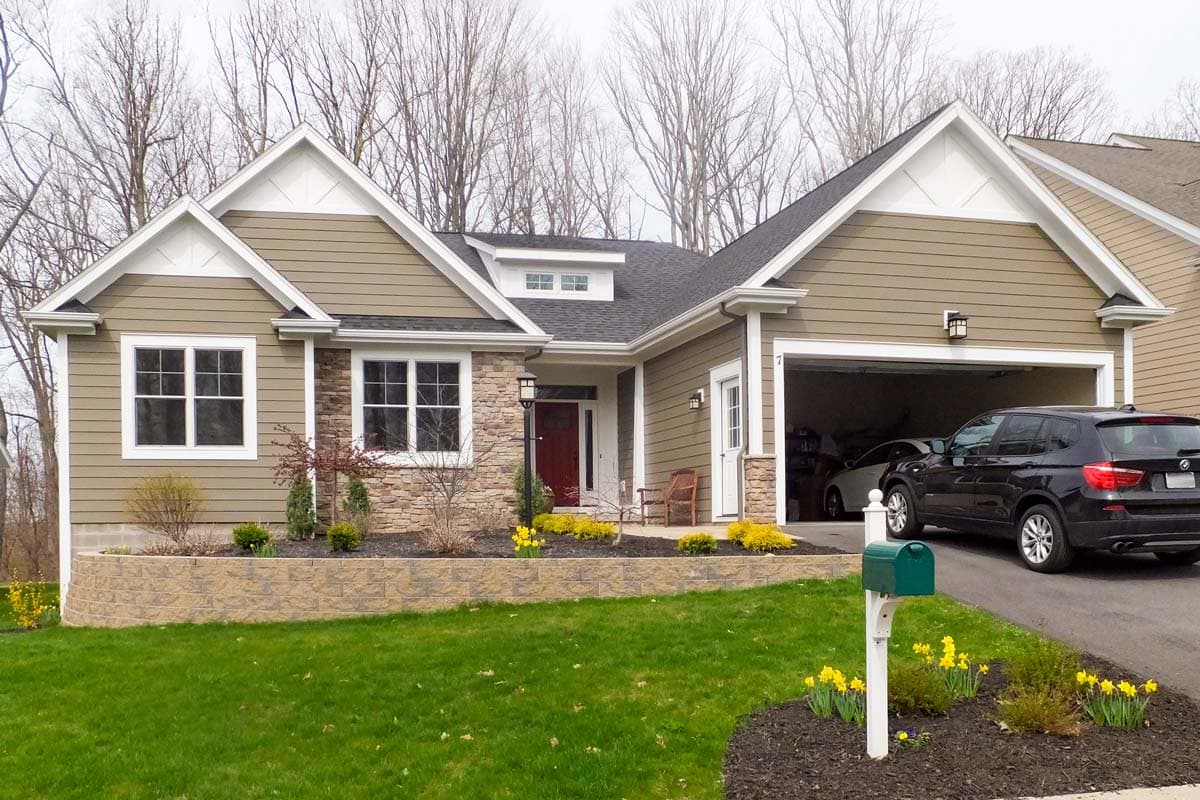 House plan exterior: Modern Farmhouse style, 1-story, with stone accents, prominent gables, dormer, and 2-car garage.