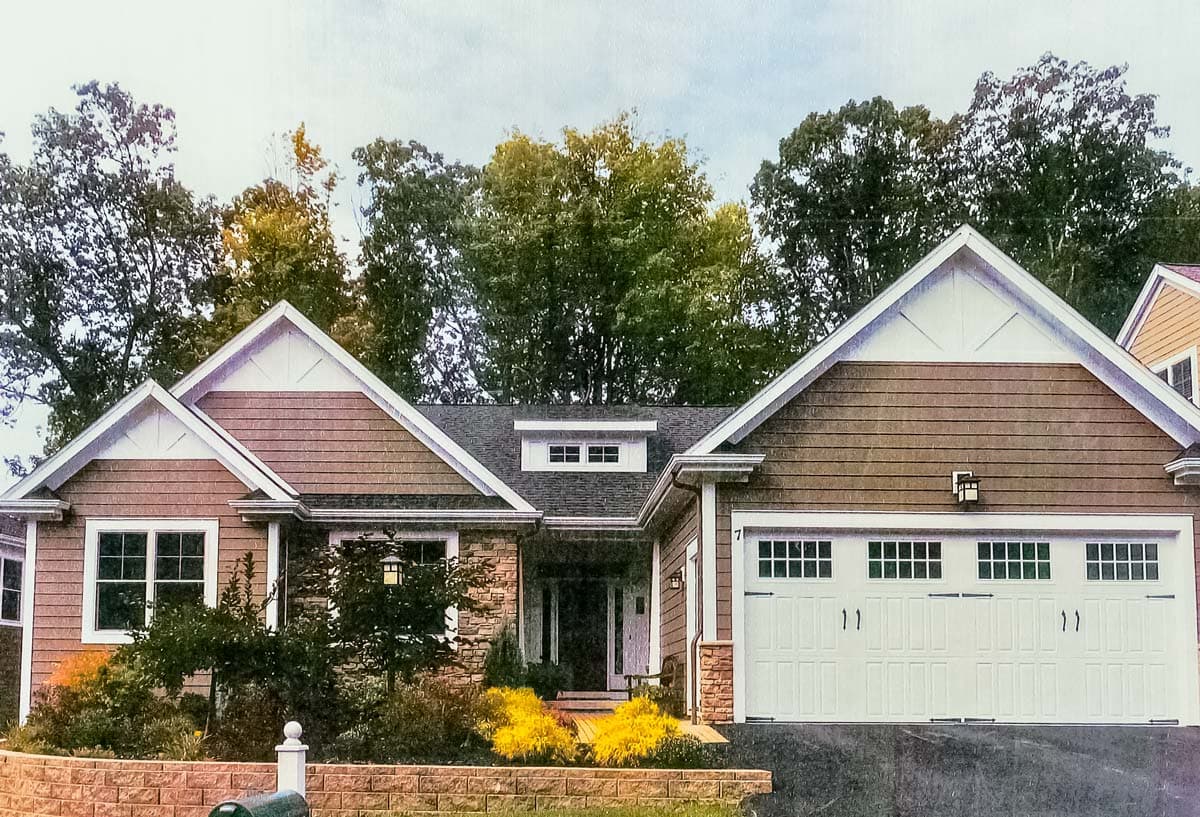 House plan exterior: Ranch style with prominent gables, horizontal siding, stone accents, and a three-car garage.