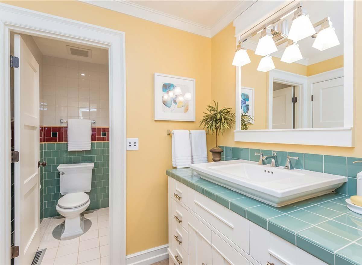 Bathroom with green tiled half-wall, white vanity, and separate toilet area with tiled walls.