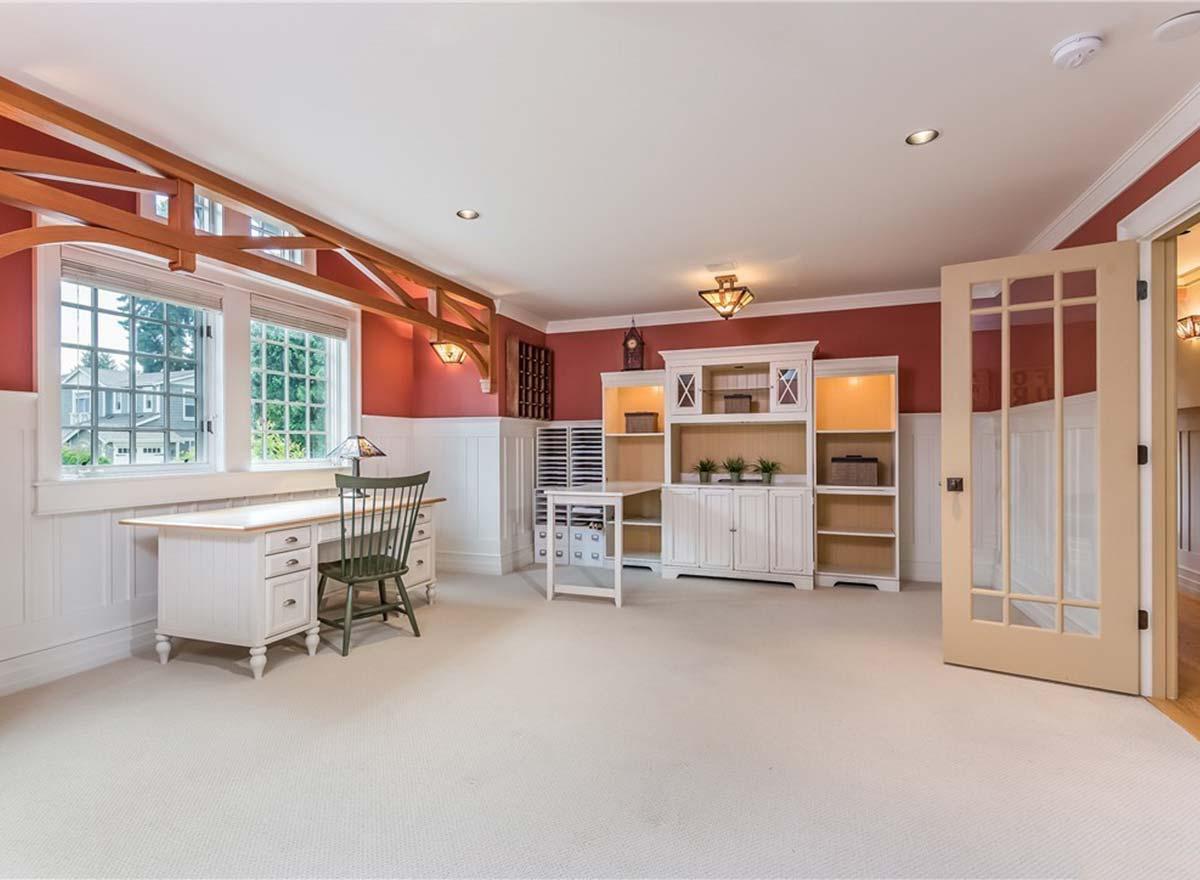 Interior view of a craft room with a desk, built-in shelving, and decorative wooden beams under a vaulted ceiling.
