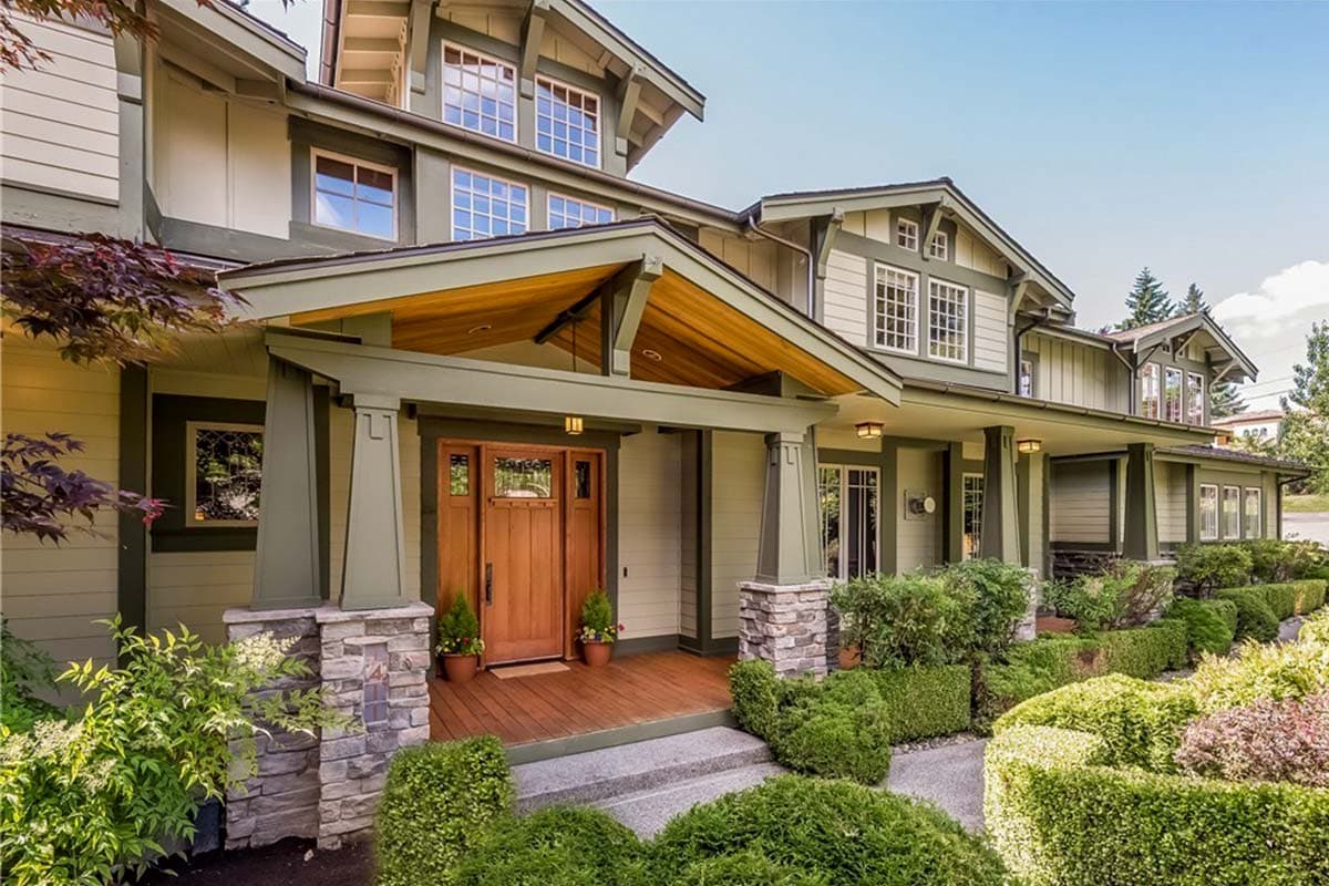 Craftsman style house plan exterior with prominent porch, stone-clad columns, gabled dormers, and multi-pane windows.