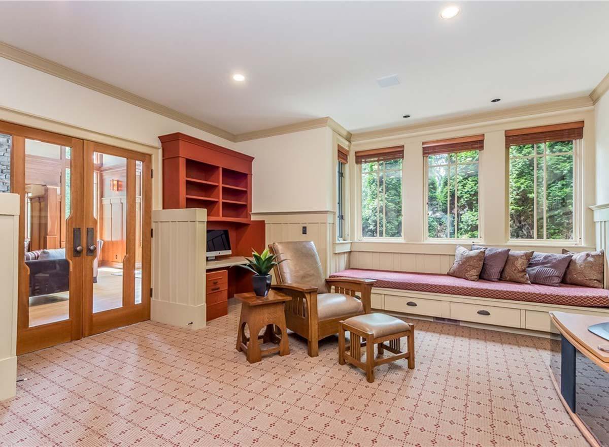 Interior view of a room with a built-in desk, chair, ottoman, and window seat with storage.