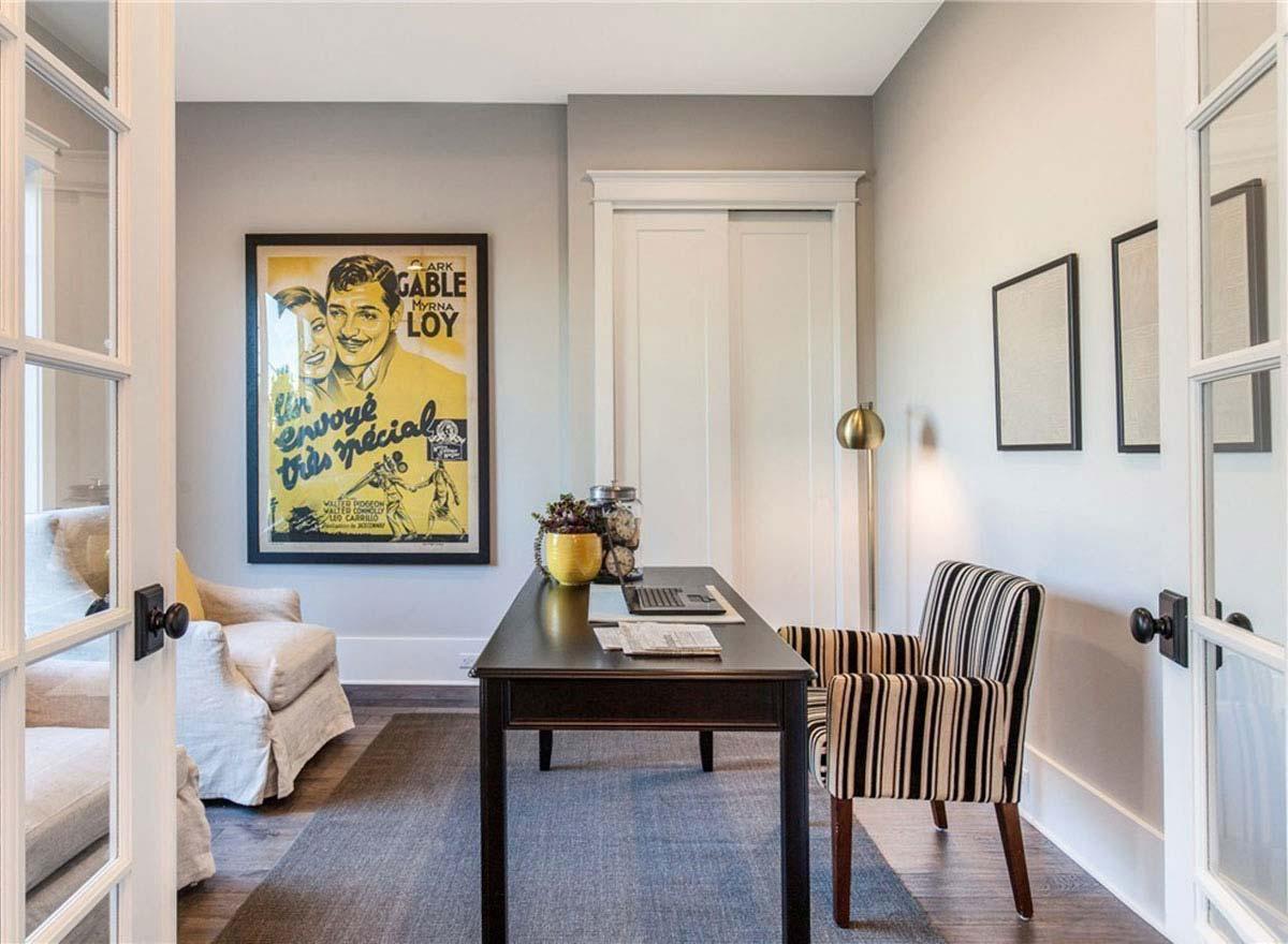 Home office with a desk, chairs, large movie poster, and French doors.