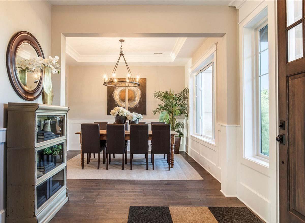 Dining room with coffered ceiling, chandelier, large windows, and entry foyer with mirrored cabinet.