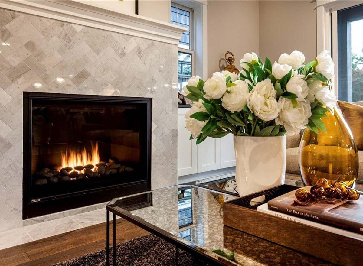 Interior view: Contemporary living room featuring a gas fireplace with marble tile surround and white floral arrangement.