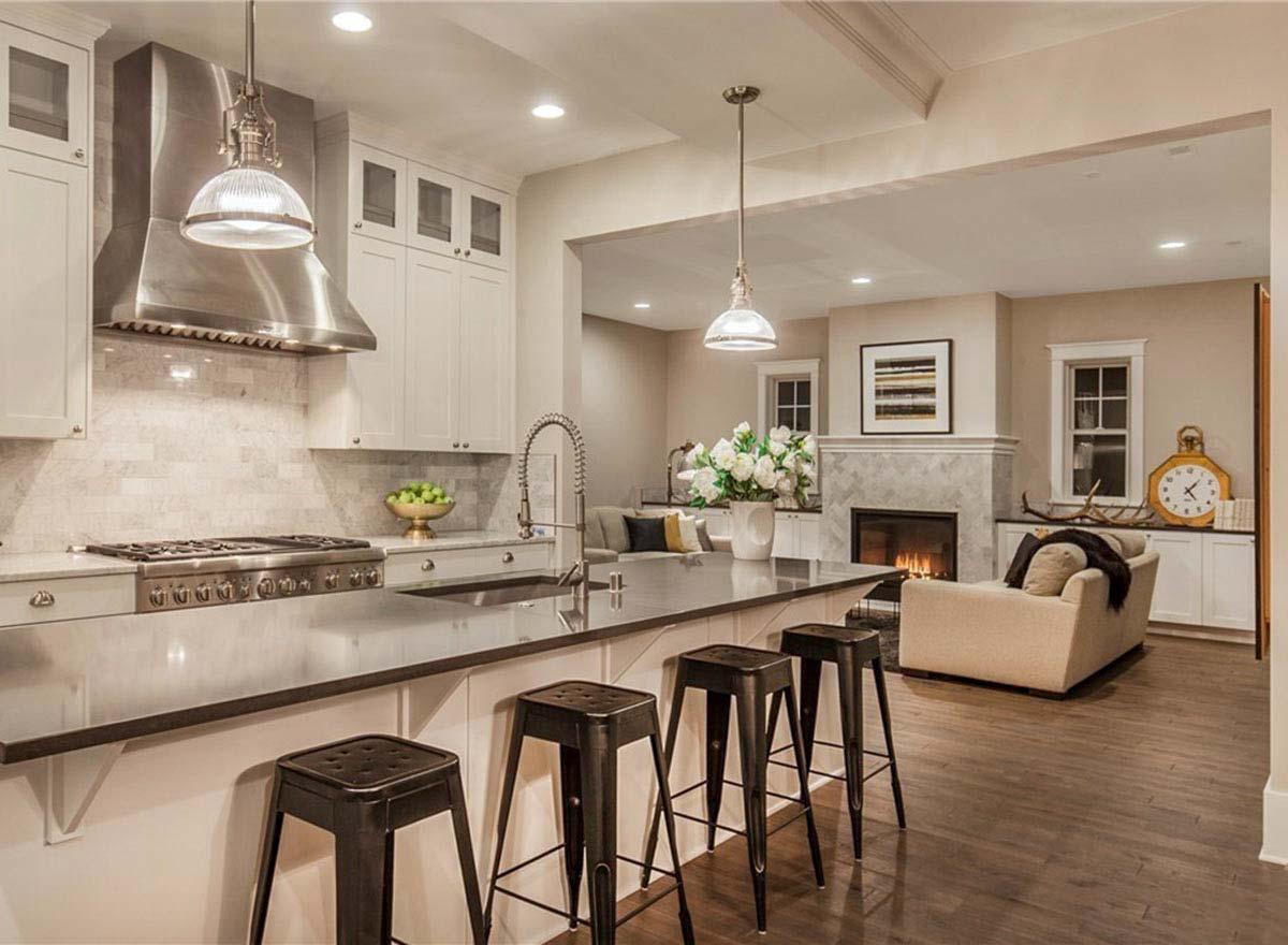 Kitchen with island seating and open view to a living room with fireplace.