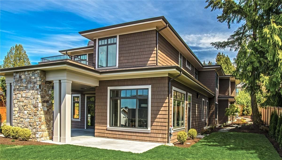 Modern house plan exterior with stone accent pillars, multiple rooflines, large windows, and second-story balcony.