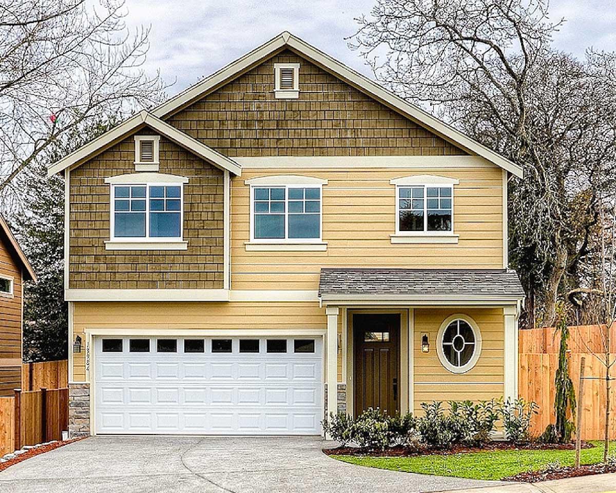 House plan exterior. Two-story Craftsman home with a gabled roof, shake siding on the upper story, and a two-car garage.