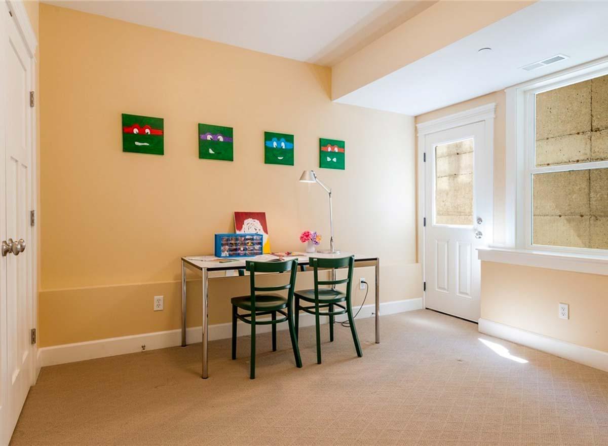 Interior view of a children's study area with a desk, two chairs, and artwork on the wall.