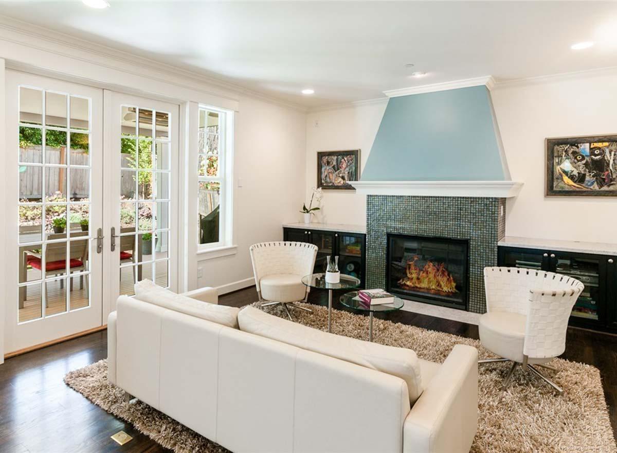 Living room interior with fireplace, double French doors leading to an outdoor patio, and white sofa.