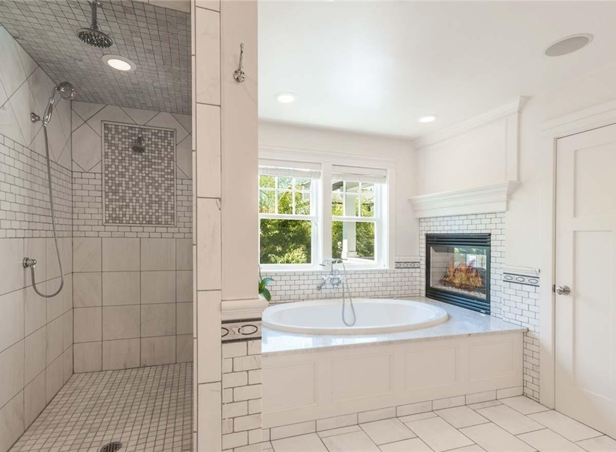 Luxury bathroom with walk-in shower, oval soaking tub, and gas fireplace. Tiled walls and floors.