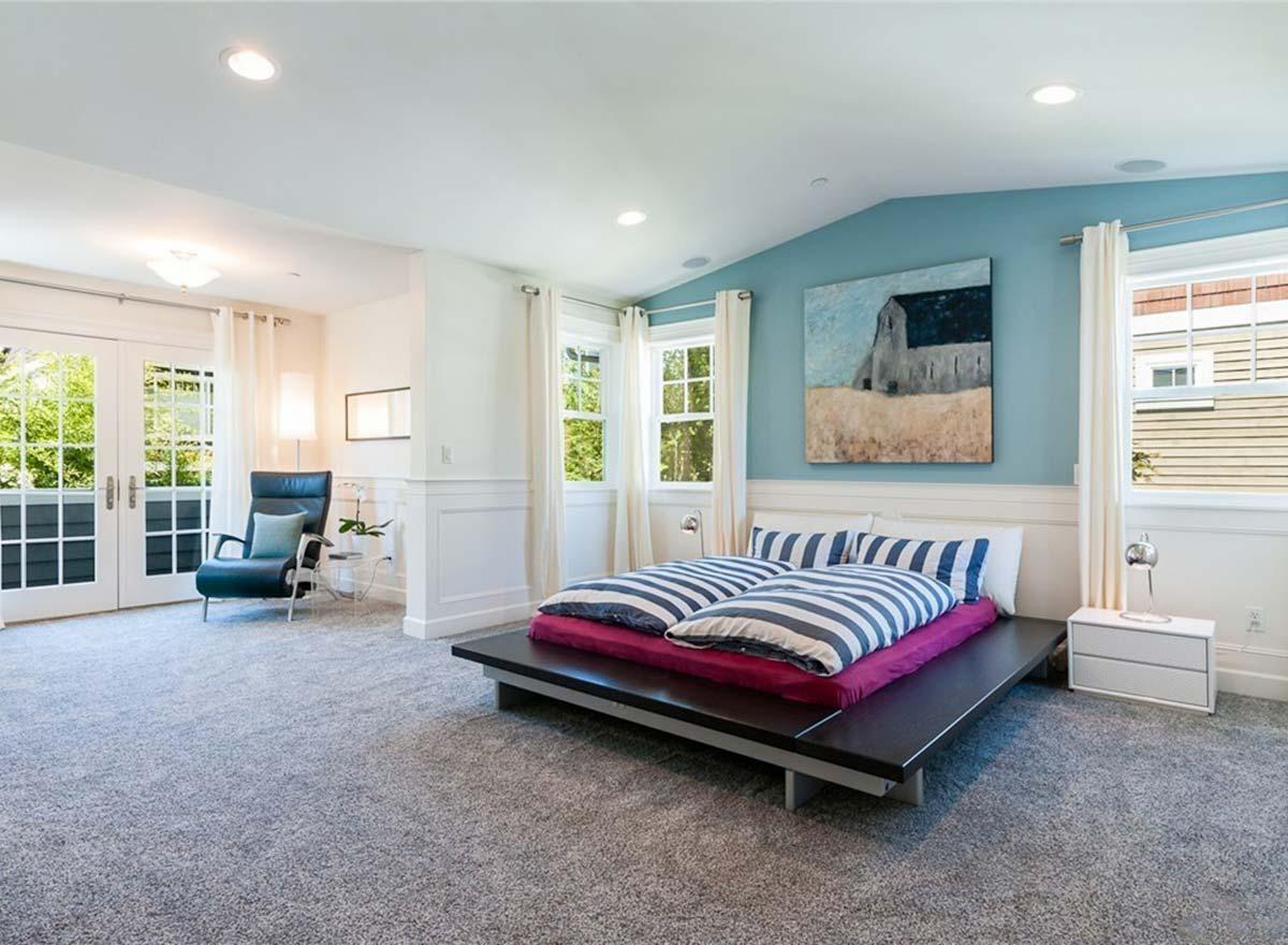 Bedroom with platform bed, accent wall with barn painting, French doors, and multiple windows.