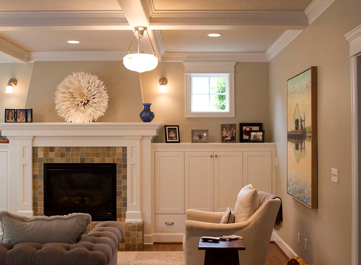 Interior view of a living room featuring a fireplace with tiled surround, built-in cabinetry, and coffered ceiling.