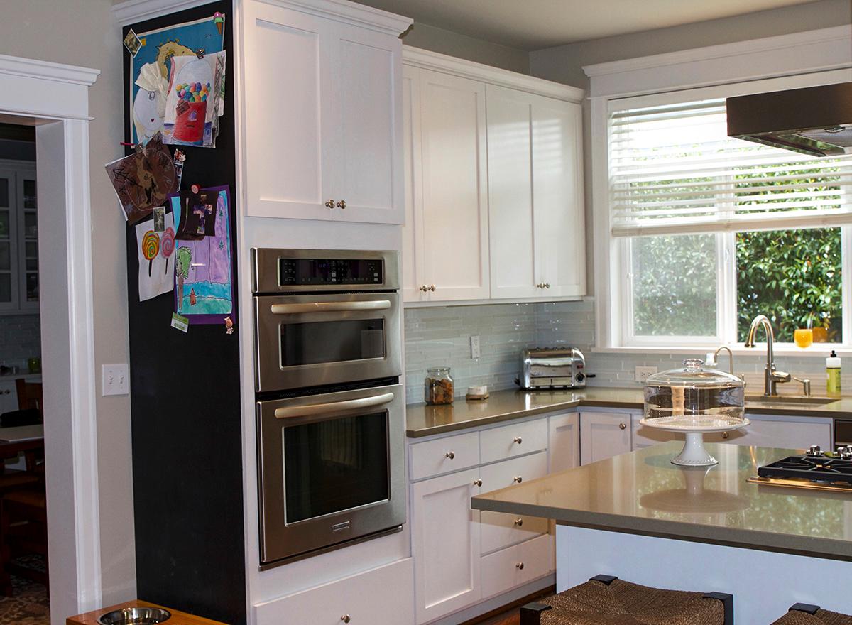 Kitchen featuring white cabinetry, stainless steel double oven, subway tile backsplash, and a kitchen island.