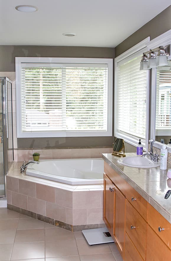 Bathroom with corner soaking tub, double vanity with wood cabinets, and corner shower.